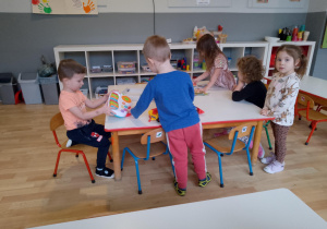 Sala przedszkolna. Dzieci bawią się przy stoliku.