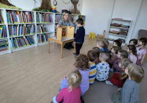 Biblioteka ,,Ferment". Dzieci siedzą na dywanie, słuchają opowieści w formie teatru Kamishibai.