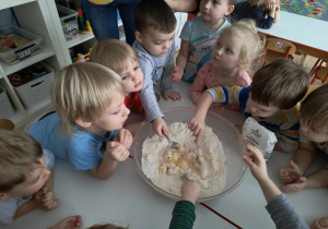 Sala przedszkolna. Dzieci mieszają składniki na ciasteczka w misce.
