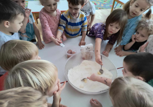 Sala przedszkolna. Dzieci mieszają składniki na ciasteczka w misce.