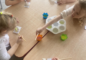 Dzieci przy stole malujące baranki z masy solnej farbami