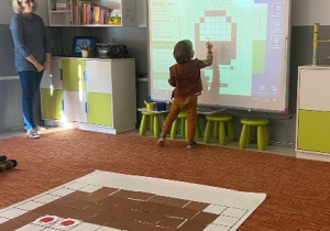 Chłopiec rysuje owoce na wirtualnej macie do kodowania.