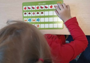 Dziewczynka układa obrazki kontynuując podaną sekwencję